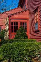 Red historic home with green bushes in autumn
