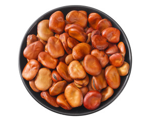 dried broad beans in black bowl isolated on white background. top view