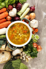 Broth with noodles and carrots, various fresh vegetables in a pot - colorful fresh clear spring soup. Rural kitchen scenery vegetarian bouillon stock