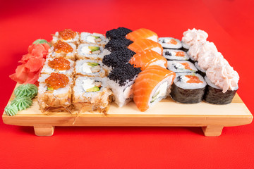 Assorted rolls and poppies. On the plank. On a red background.
