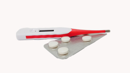 Digital thermometer and white fever pills isolated in white background