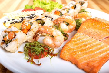 Assorted sushi, shrimp, and a piece of grilled salmon.