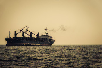 Obraz premium cargo ship in the sea at sunset