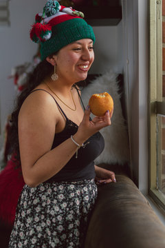 Colombian woman at Christmas with Christmas hat eating bu&ntilde;uelo typical Colombian food