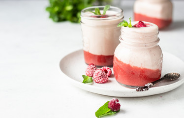 Healthy layered raspberry and yogurt smoothie or cocktail in mason jar with fresh berries and mint. Well being and weight loss concept. Natural detox.