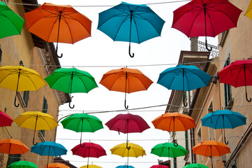 Colored umbrellas attached to the wires in a small town in Italy