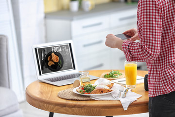 Food blogger taking photo of her lunch at wooden table indoors, closeup