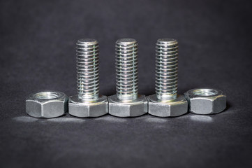Metal bolts and nuts on black background are used in construction
