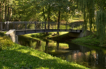 Fototapeta na wymiar Footbridge over Lyna river and alley Chateauroux at Park Podzamcze in Olsztyn. Poland 