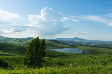 Russian green hills and meadows in Altai. Aya Lake for tourists. The sun and sunset of the day. Summer and grass. Nature travel
