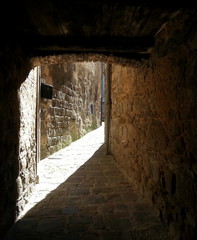 A stream of light shining through a narrow stone alley in a medieval italian  village