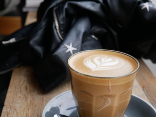 Artisan Latte Coffee with Tulip Art on Top next to Leather Jumper