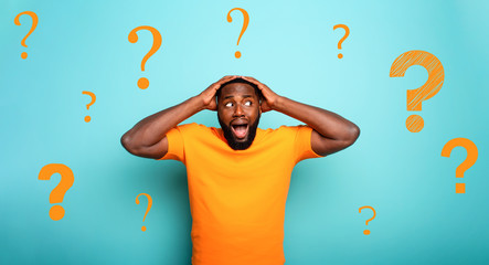 Feared and shocked expression of a boy with many questions . cyan colored background