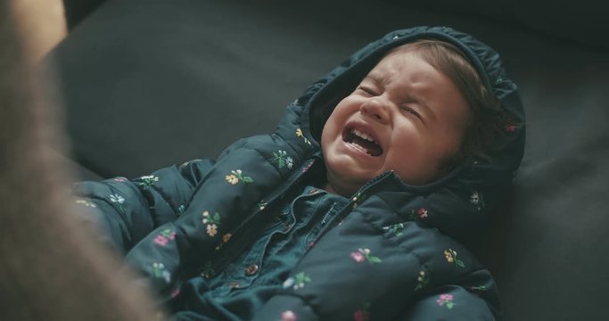 Baby toddler girl being dressed to go outside in the cold. Cinematic 4K footage.
