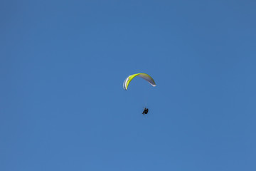 a man paragliding solo on the blue sky over the Dolomites in Italy in a sunny day