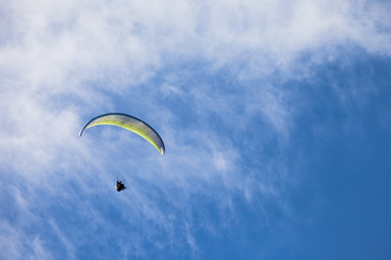 a man paragliding solo on the blue sky over the Dolomites in Italy in a sunny day