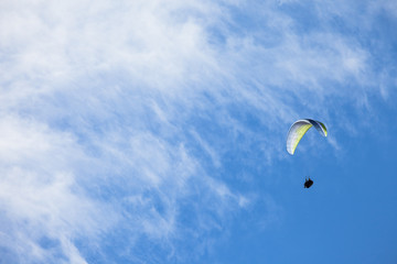 a man paragliding solo on the blue sky over the Dolomites in Italy in a sunny day