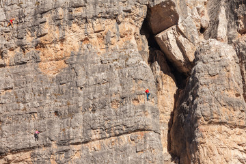 Rock climbers in action over a vertical cliff in the Cinque Torri area in Dolomites