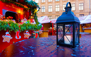 Street lamp with candles at Christmas Market at Riga in Winter Latvia. Light lantern on Advent Fair Decoration and Stalls with Crafts Items on Bazaar. Latvian street Xmas and holiday