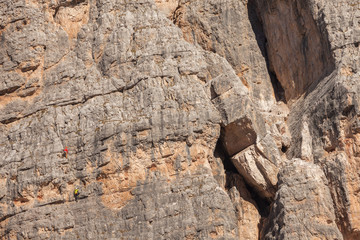 Rock climbers in action over a vertical cliff in the Cinque Torri area in Dolomites