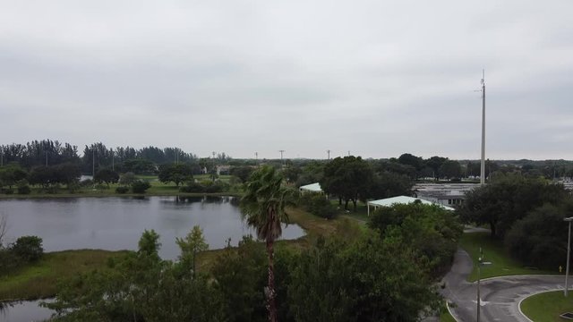 a video from a drone accending in front of a lake with green trees and grass background surrounding it