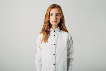 A young red-haired girl is looking at the camera. A student with red hair suffers from bullying. Isolate on a white background.