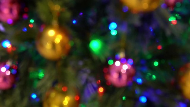 Christmas decoration with hanging ornaments and lights on tree, defocused with blurred colorful blinking  lights bokeh in 4k