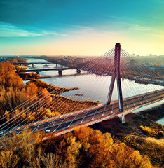 Beautiful panoramic aerial drone sunset view to Warsaw city center with skyscrapers and Swietokrzyski Bridge (En: Holy Cross Bridge) - is a cable-stayed bridge over the Vistula river in Warsaw, Poland - obrazy, fototapety, plakaty