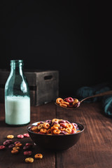 Bowl of milk and rings of colored cereals, a bottle of milk and a spoon full of cereals. Copy space design