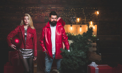 Christmas tree. Beautiful Couple dressed in a Santa hat. Handsome bearded hipster Santa with smiling positive young woman. Having a crazy day with friend.