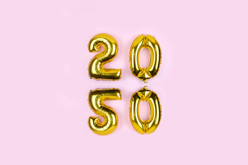 2020 numbers golden foil balloons mirror reflection on pink background. New year holiday party decoration. Metallic air balloons for New Year's Eve.