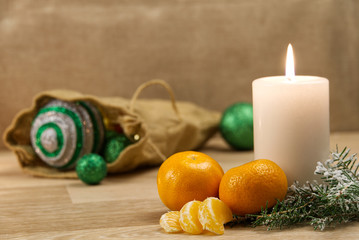 Burning candles and christmas decorations. Green balls for Christmas tree and fir twig on wooden floor with bokeh background. Copy space
