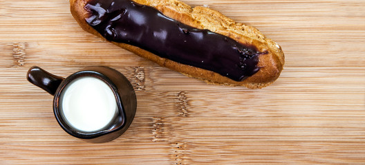 Fresh chocolate eclair & cream. Food concept in panorama / banner / header design - with text space.