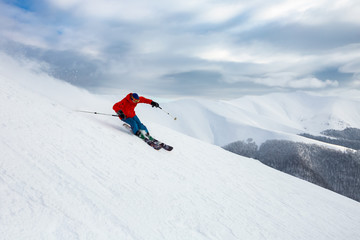 A skier in the red jacket is riding fast.