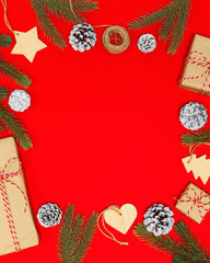 2020 New year composition. Stylish decor concept, christmas wooden toy, kraft paper gift box, fir cones branches on red backdrop. Flat lay, top view, copy space. Background for postcard, for desktop