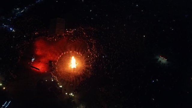 Lots of people crowd celebrate. Ethnic festival holiday with big bonfire. Folk feast concert in the countryside in a rural night landscape. Aerial survey 