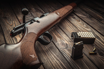 Classic bolt carbine .22lr with a wooden butt on a dark wooden surface. Weapons and cartridges for...