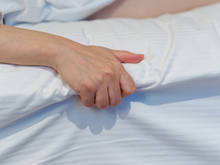 Close up image of Asian woman hand grasp white bed sheet.