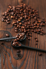 Spoon with roasted coffee beans on wooden background