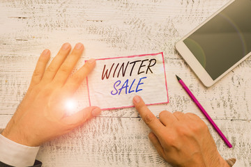 Obraz premium Writing note showing Winter Sale. Business concept for Discounts offered at the end of year Holiday sales lower prices Hand hold note paper near writing equipment and smartphone