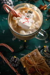Christmas composition. Or happy new year. Vertical frame with a latte mug and a snowman with marshmallows.