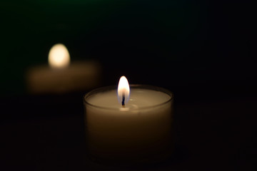 Obraz na płótnie Canvas Kerze leuchtet im Dunkeln - kleine weiße Kerze auf schwarzem Hintergrund