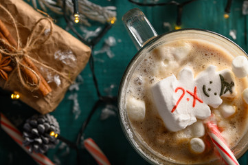 Obraz na płótnie Canvas Christmas composition, mug with hot chocolate with melted snowman marshmallows and caramel. horizontal frame over green background