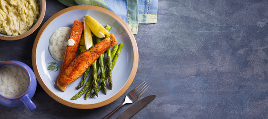 Salmon fish fillet with asparagus and creamy garlic sauce. View from above, top. Copy space