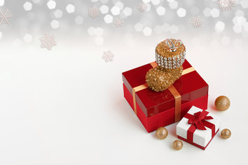 Red gift box wrapped with golden ribbon and white gift box wrapped with red ribbon on Christmas ornaments. White bokeh background and copy space. 
