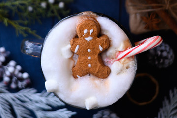 Christmas and New Year. Marshmallow snowman in hot latte in a mug. On the background of Christmas trees and toys.