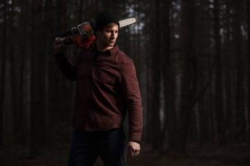 Lumberman working with chainsaw in the forest. Strong lumberjack with the chainsow in the...