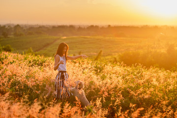 Fototapeta premium Trendy girl in stylish summer dress feeling free in the field with flowers in sunshine.