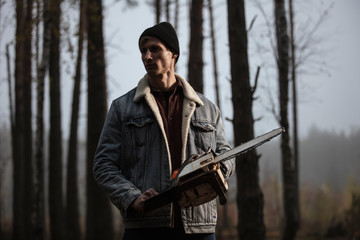 Lumberman working with chainsaw in the forest. Strong lumberjack with the chainsow in the...