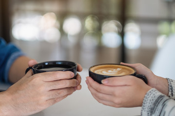 Fototapeta premium Closeup image of a man and a woman holding two coffee cups together